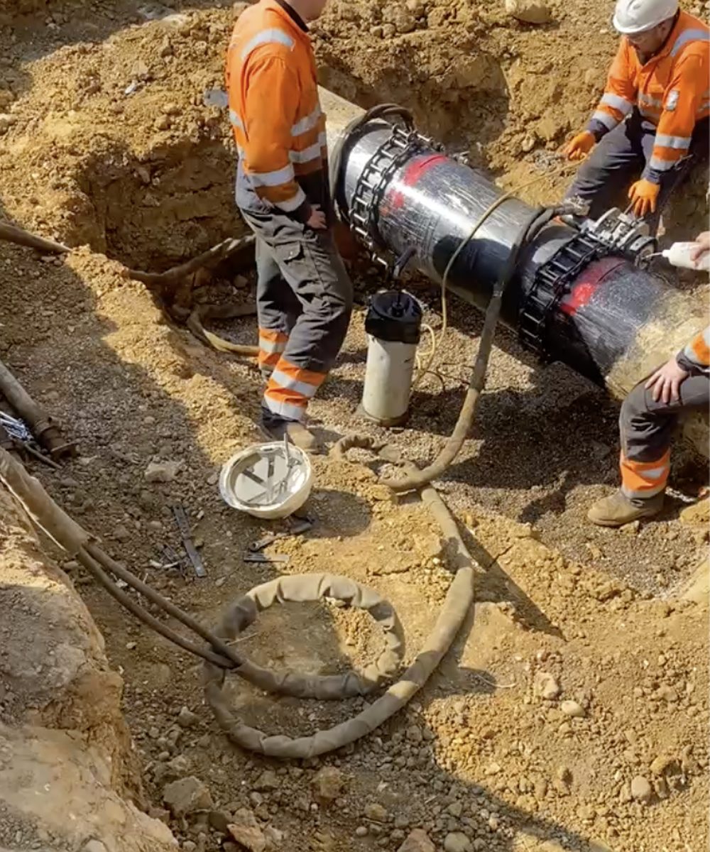 Two operatives fitting a mechanical coupling to a medium-pressure main