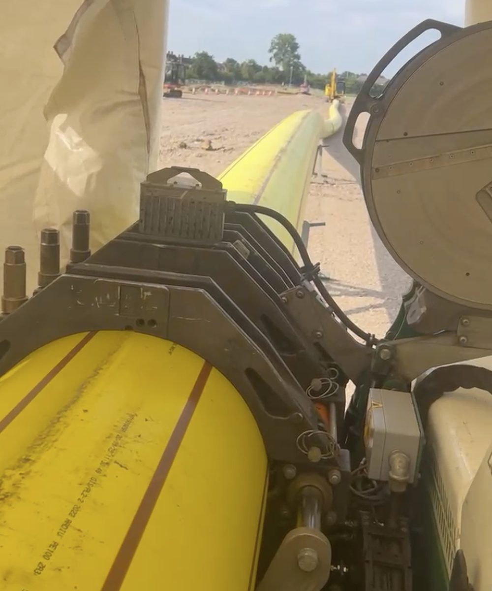 Butt fusion machine welding two lengths of large-diameter yellow PE pipe
